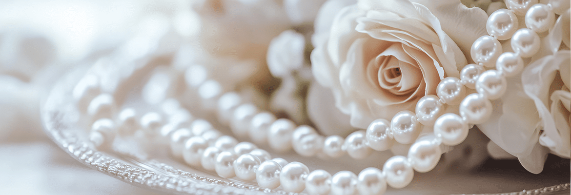 strands of pearls in font of a bouquet of roses