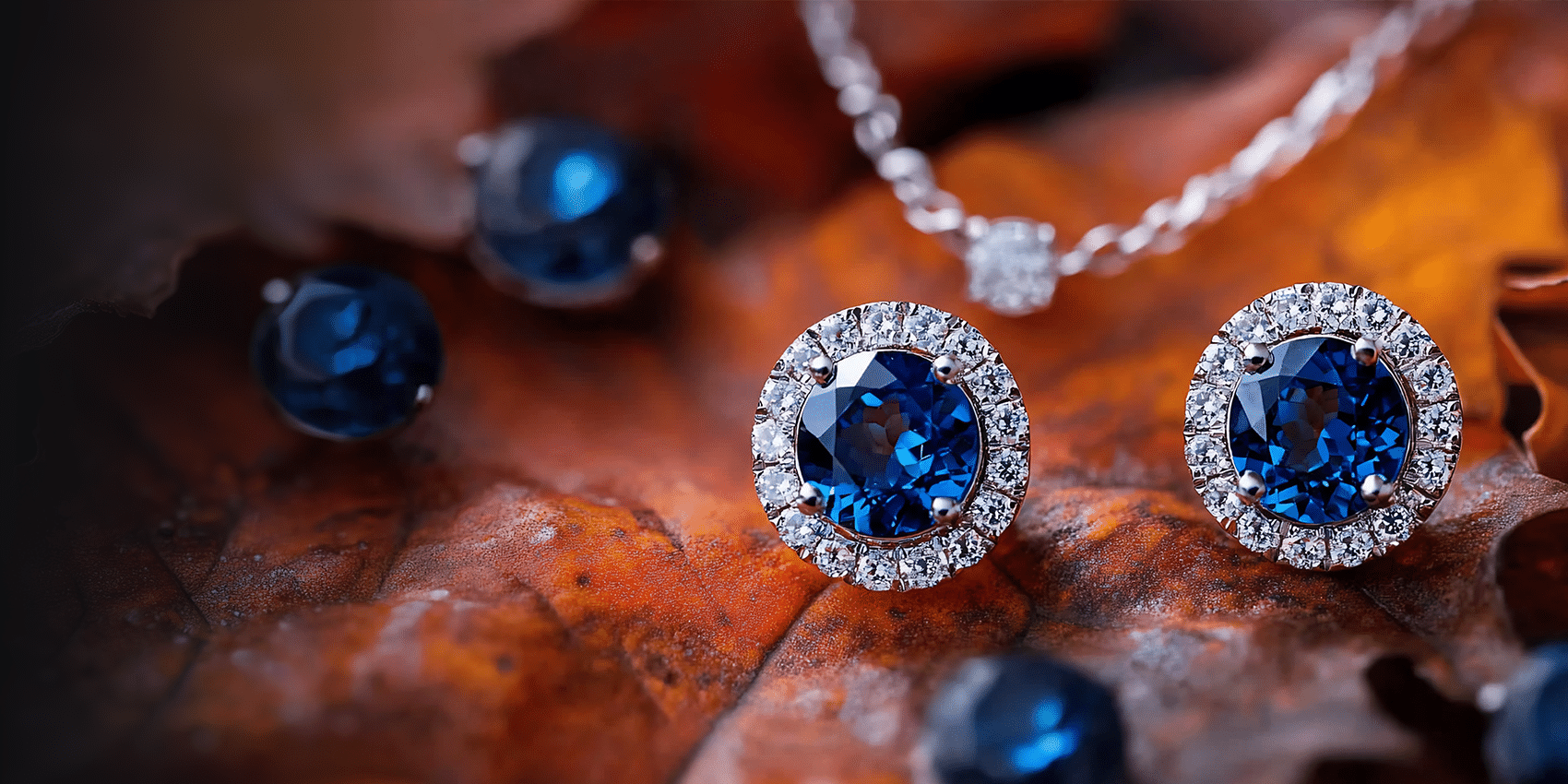 round blue sapphire earrings with diamonds sitting on brown and red fall colored leaves